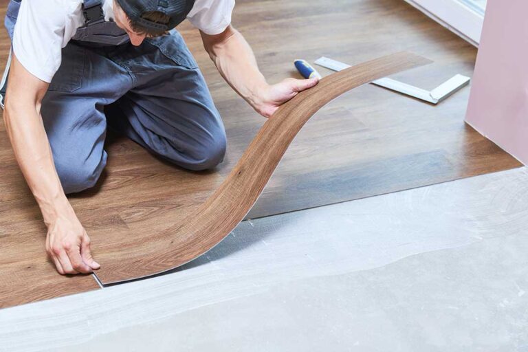 Wide-plank light wood flooring in a bright living room with a dog resting near a sunny window.